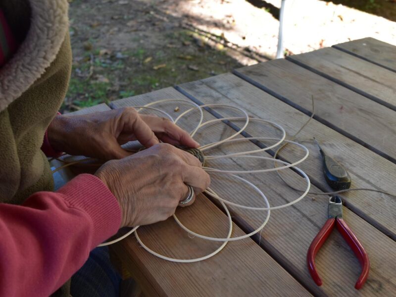 Vannerie : mains tressant des brins d’osier autour d’un fond de panier