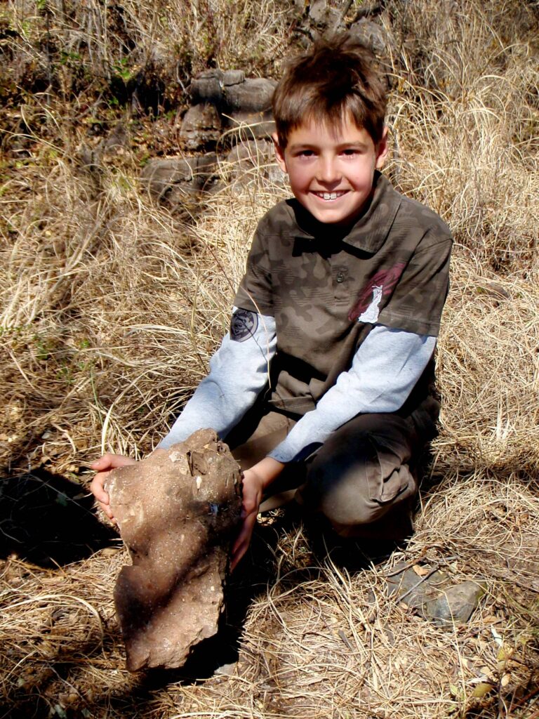 Un enfant tient un bloc de roche contenant un fossile