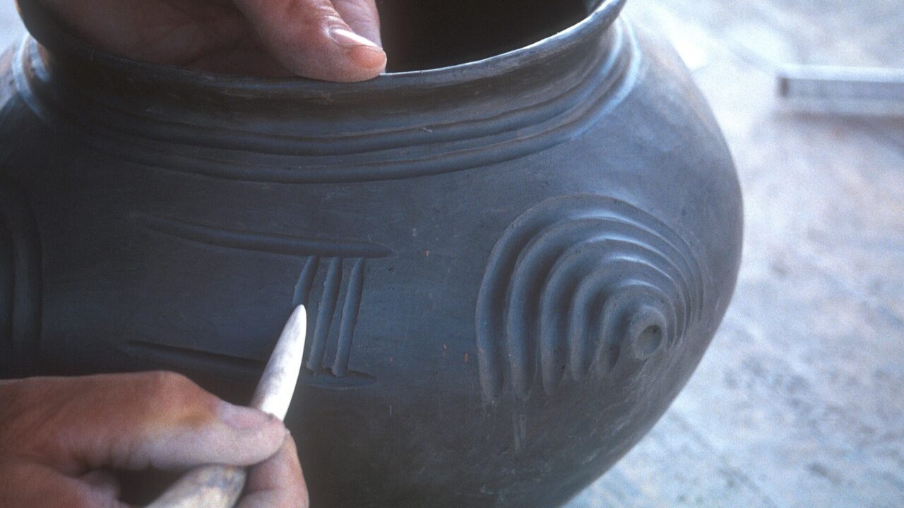 Mains décorant un vase en céramique avec un outil, archéologie expérimentale