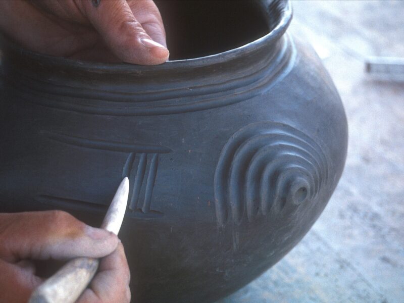 Mains décorant un vase en céramique avec un outil, archéologie expérimentale