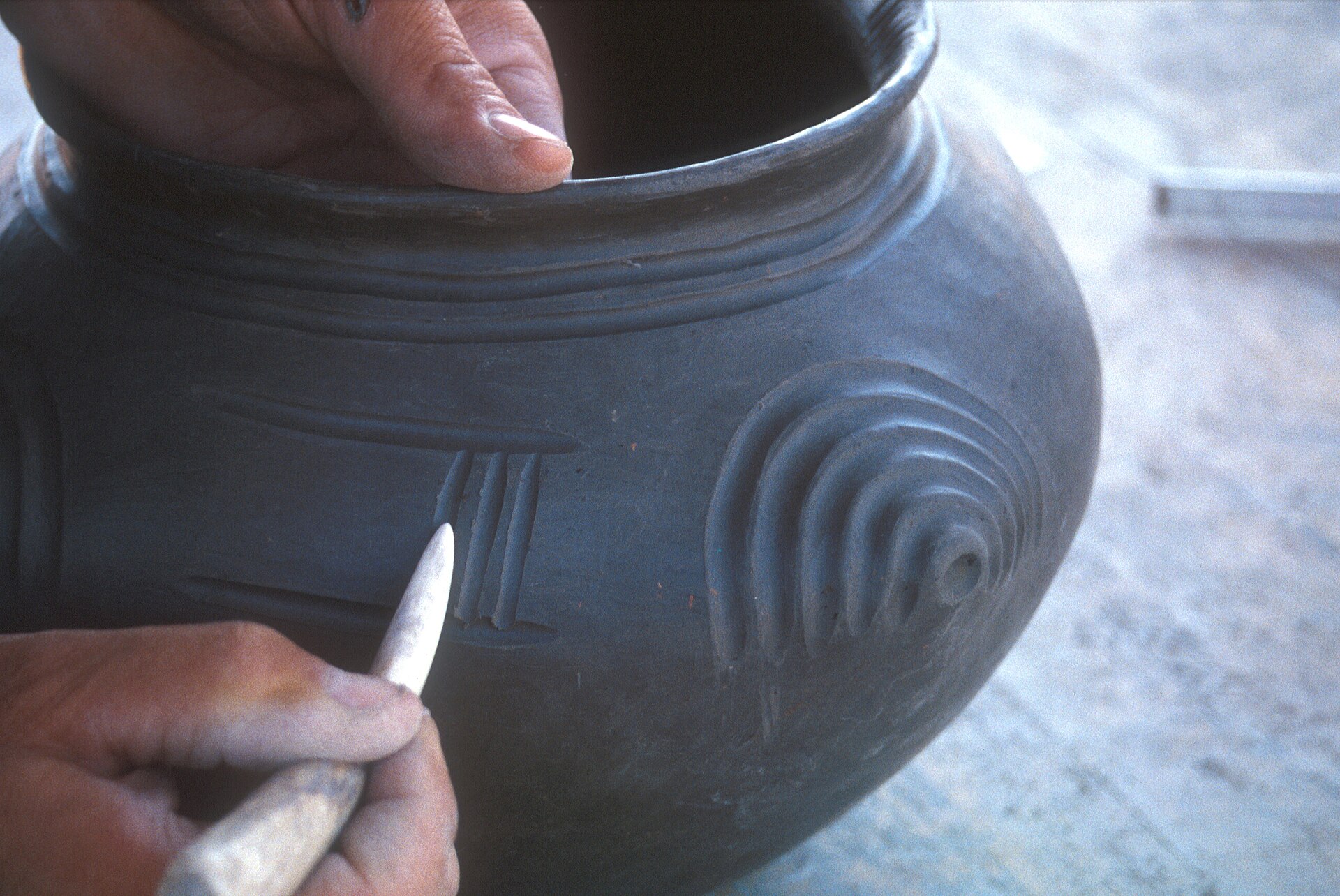 Mains décorant un vase en céramique avec un outil, archéologie expérimentale