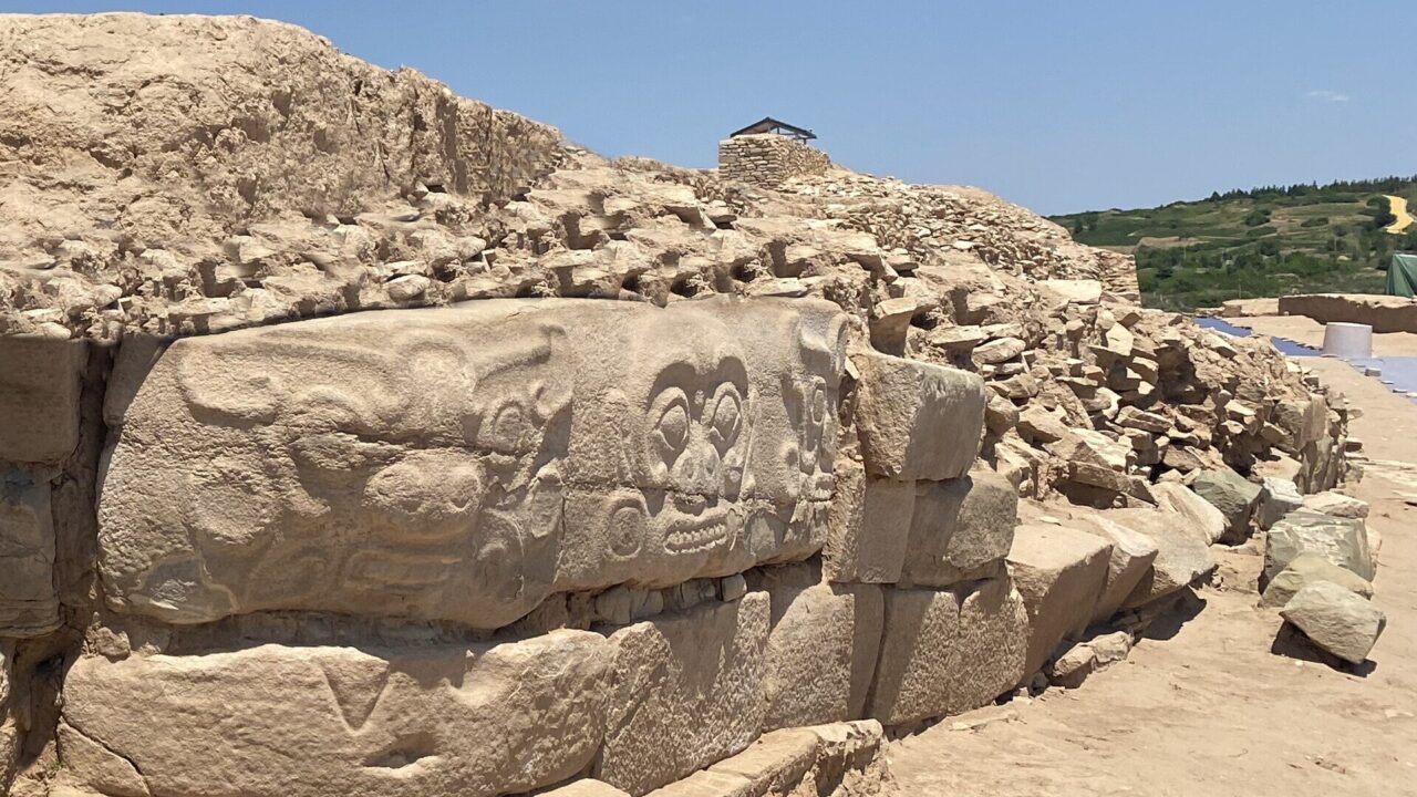 Mur de pierre de la cité de Shimao, orné de frises sculptées de visages et d’animaux.
