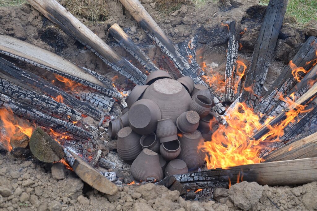 Poteries en cours de cuisson dans une fosse entourée de bois enflammé