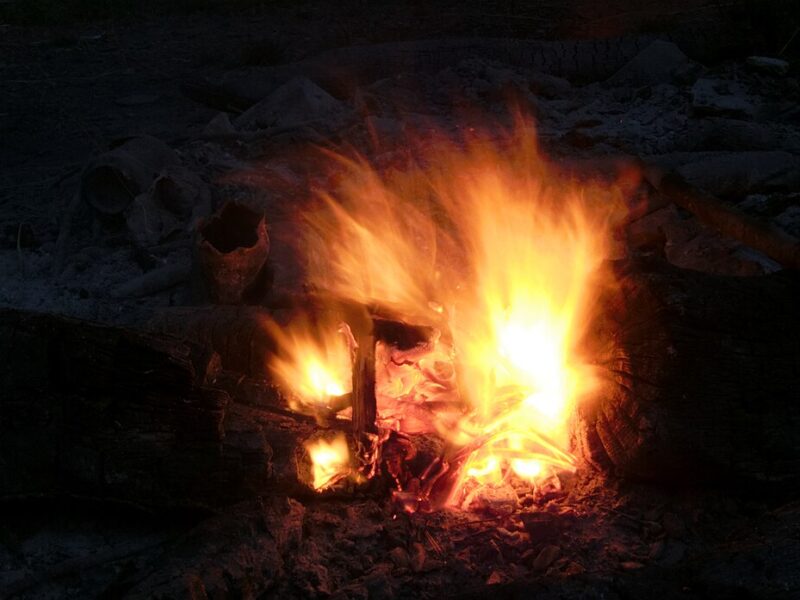 Flammes d’un feu entretenu entre des pierres, la nuit