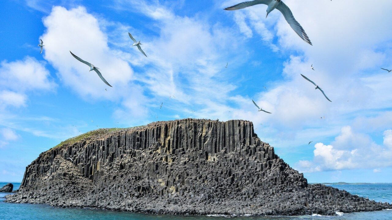 Îlot de colonnes basaltiques de l'archipel des Pescadores, cerné d'une mer turquoise et survolé par des sternes.