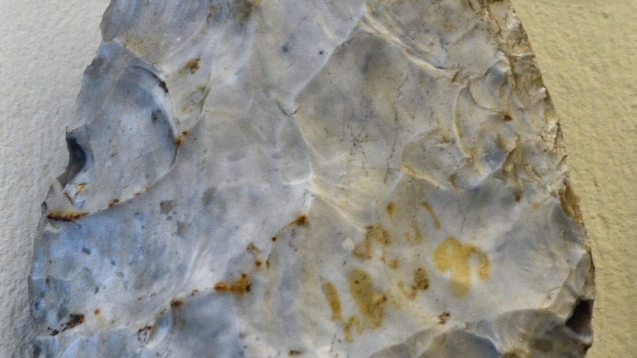 Biface en silex gris, de forme cordiforme, sur fond clair