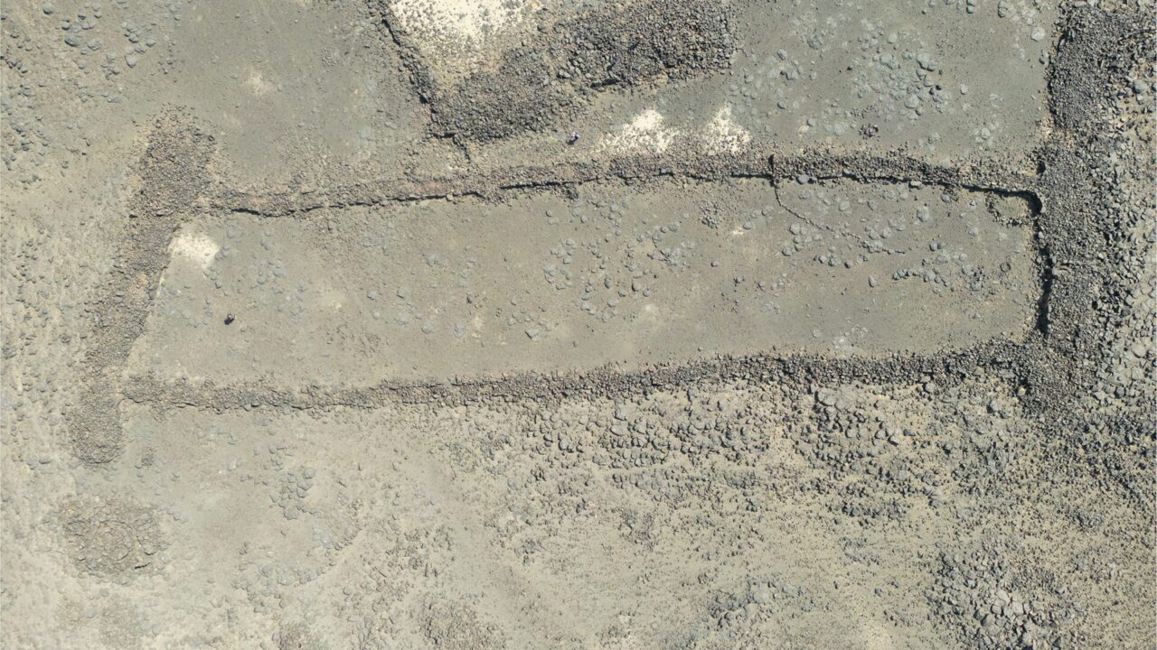 Vue aérienne d’un mustatil, long rectangle de murs de basalte sur un plateau de lave