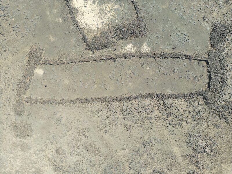 Vue aérienne d’un mustatil, long rectangle de murs de basalte sur un plateau de lave